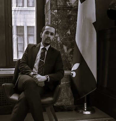 Karim Lahnin seated beside a Quebec flag